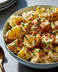 Bowl of classic potato salad garnished with herbs and spices.