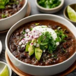 A bowl of classic black bean soup garnished with cilantro and lime.