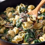 Creamy spinach mushroom tortellini served in a bowl with herbs