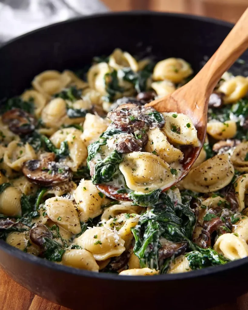 Creamy spinach mushroom tortellini served in a bowl with herbs