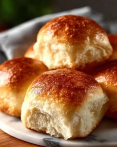 Freshly baked easy homemade dinner rolls on a wooden table.