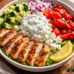 Delicious Chicken and Tzatziki Bowls topped with fresh vegetables and herbs.