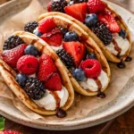 Pancake tacos filled with fruit and syrup on a plate