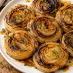 Plate of delicious roasted onions garnished with herbs.