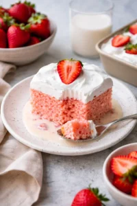 Delicious Strawberry Three Milks Cake topped with fresh strawberries and cream