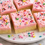 Delicious homemade sugar cookie bars topped with colorful icing and sprinkles.