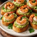 Garlic shrimp crostini topped with avocado on a serving platter