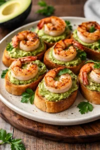Garlic shrimp crostini topped with avocado on a serving platter