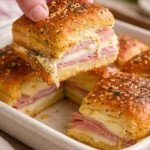 Delicious ham and cheese sliders served on a platter with herbs