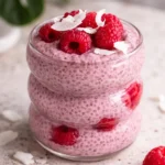 Bowl of healthy raspberry chia pudding topped with fresh raspberries and mint