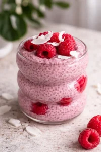 Bowl of healthy raspberry chia pudding topped with fresh raspberries and mint