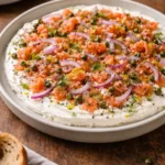 Delicious smoked salmon bagel dip served in a bowl with crackers and fresh herbs