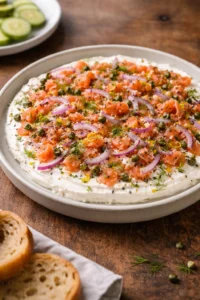 Delicious smoked salmon bagel dip served in a bowl with crackers and fresh herbs