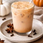 Iced pumpkin cream chai latte in a glass with whipped cream and spices