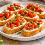 Whipped feta tomato crostini topped with fresh basil on a serving platter.