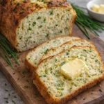 Loaf of freshly baked 2-Ingredient Cottage Cheese Bread on a wooden cutting board.