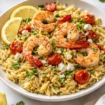 Plate of Lemon Feta Orzo with shrimp garnished with fresh herbs