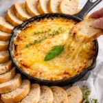 Creamy caramelized onion cheese dip served in a bowl with crackers